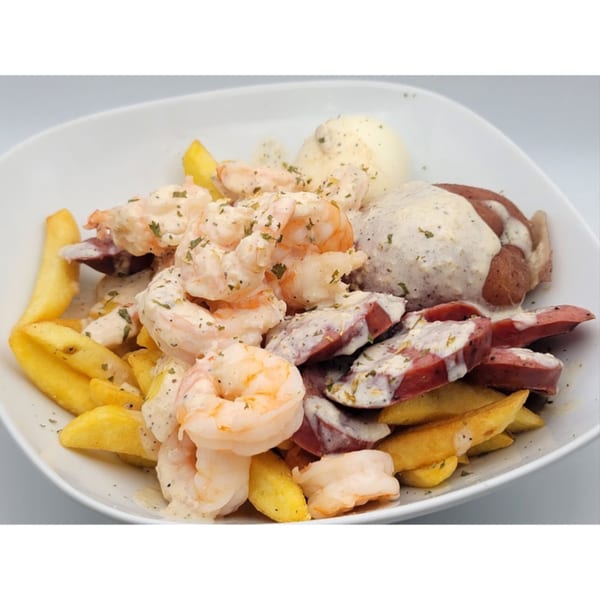 A white bowl filled with shrimp, sliced sausage, potatoes, and french fries, all covered in a creamy sauce.